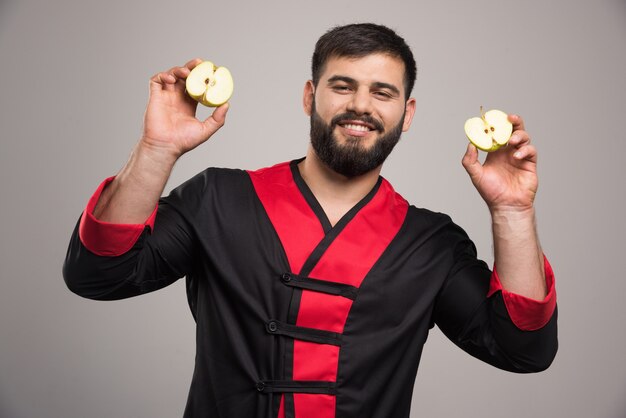 Young man showing a slices of fresh apple .