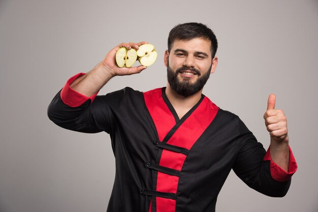 Young man showing a slices of fresh apple .