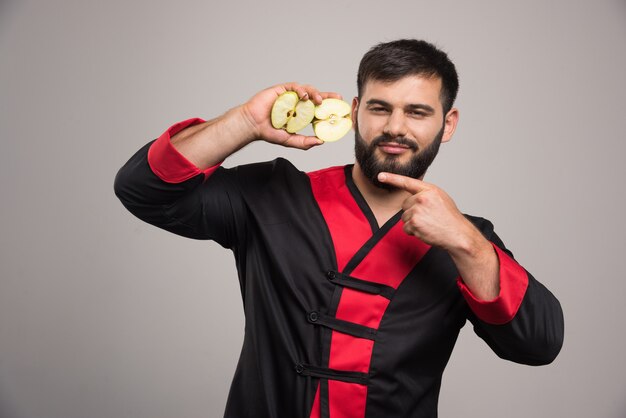 Young man showing a slices of fresh apple .