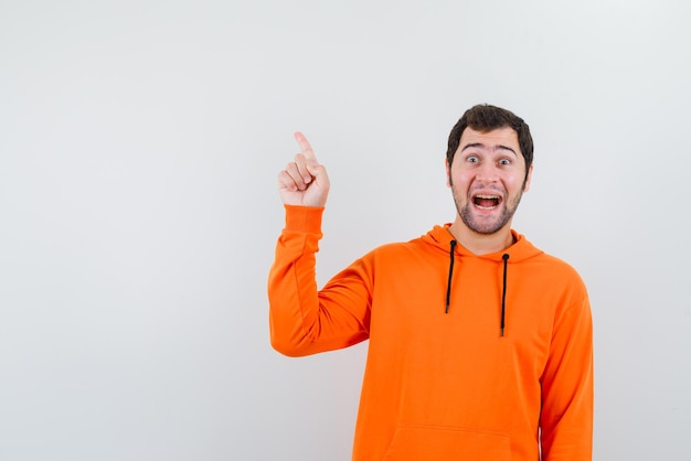 Young man showing something on the top with fingers on white background