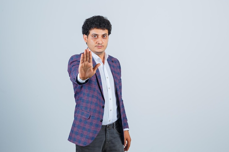 मुफ़्त फोटो young man showing stop gesture in shirt, jacket, pants and looking serious , front view.