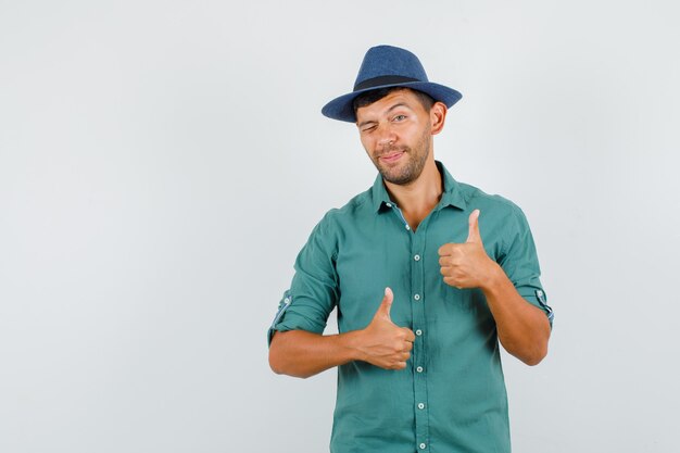 Young man showing thumbs up and blinking eye in shirt