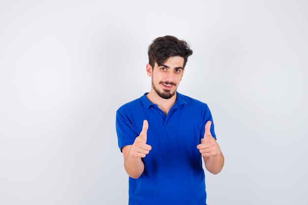 Young man showing thumbs up with both hands in blue t-shirt and looking serious
