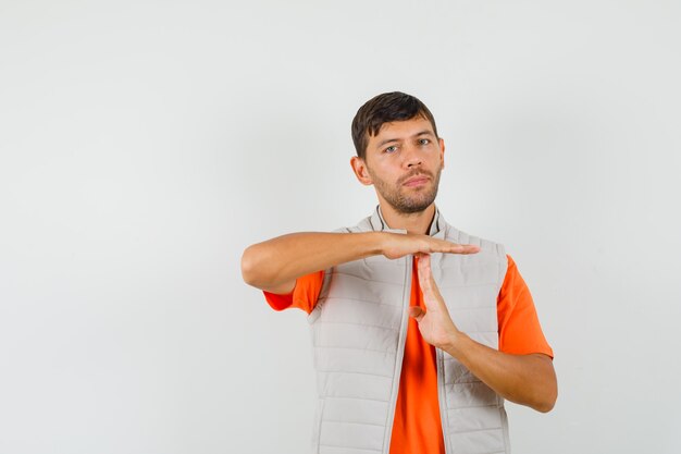 Young man showing time break gesture in t-shirt, jacket