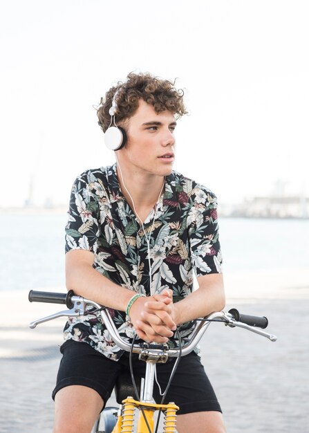 Free photo young man sitting on bicycle listening to music