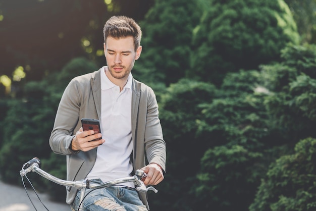 スマートフォンを見て自転車に座っている若い男