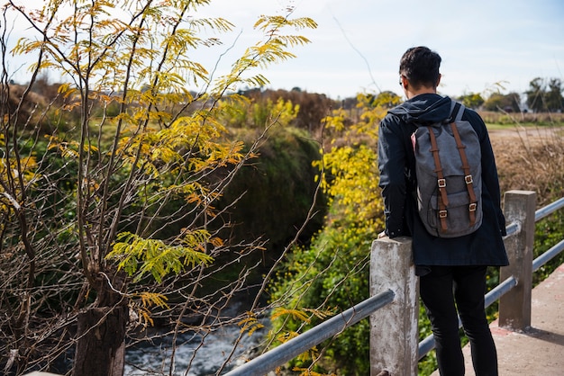 Foto gratuita giovane uomo seduto sul ponte