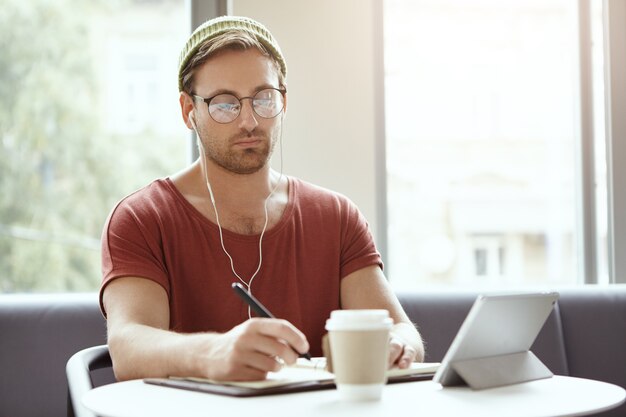 Young man sitting in cafe listening to music