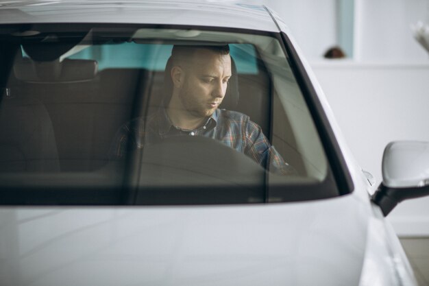 Young man sitting in car in a car showroom