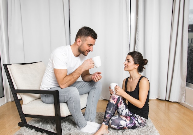 Young man sitting on chair with her girlfriend drinking the coffee at home