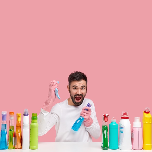 Free photo young man sitting next to cleaning products