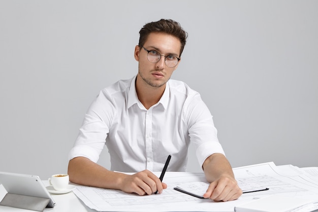 Young man sitting at desk and doing paperwork