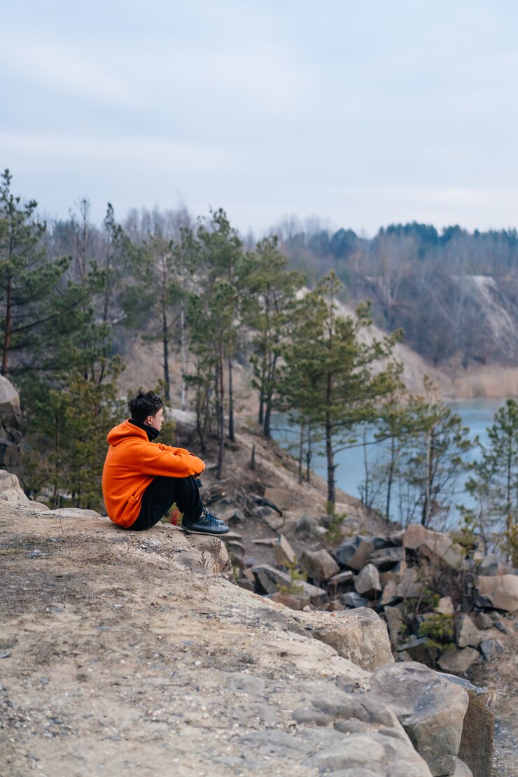Free Photo young man sitting on the edge of a cliff