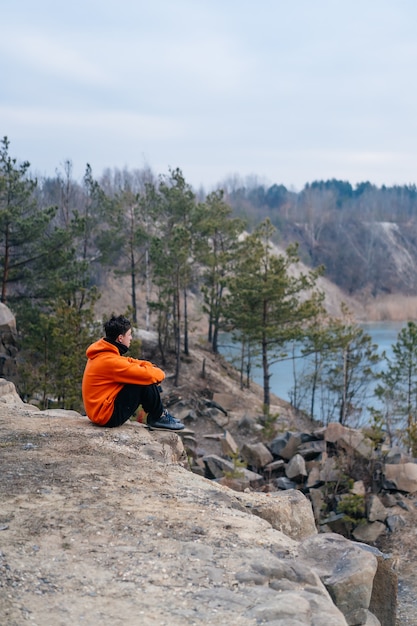 Young man sitting on the edge of a cliff