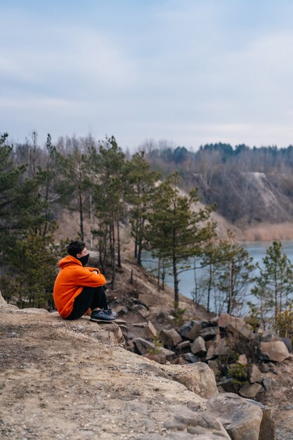 崖の端に座っている若い男