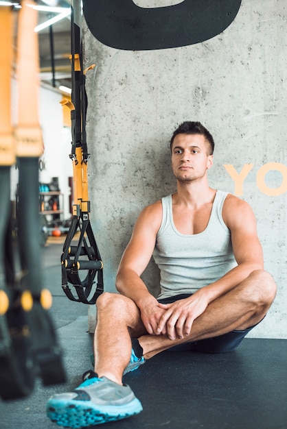 Free photo young man sitting on floor in fitness club