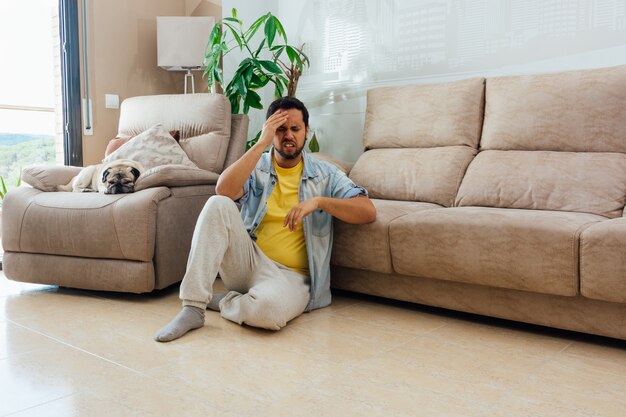 Young man sitting on the floor and holding his head in regret or disappointment