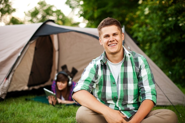 Молодой человек сидит перед палаткой