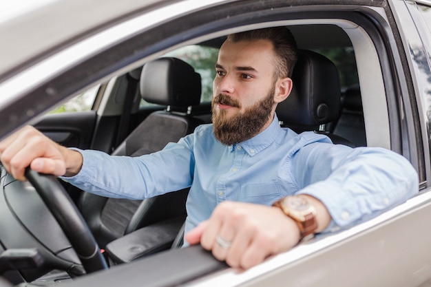 Free photo young man sitting inside car