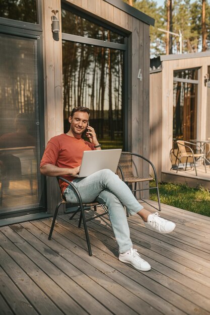 A young man sitting outside and talking on the phone