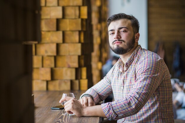 飲み物のガラスでレストランに座っている若い男