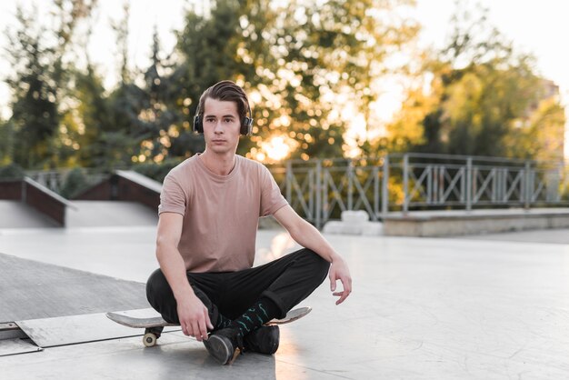 Молодой человек, сидящий на скейтборде