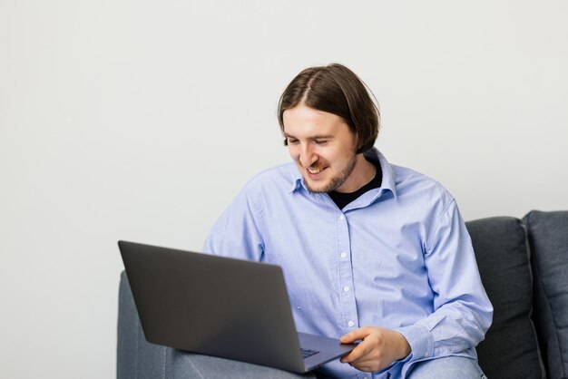 Free photo young man sitting on the sofa with laptop