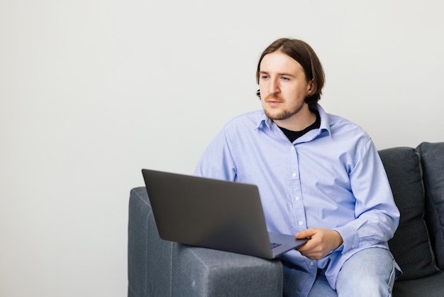 Free photo young man sitting on the sofa with laptop