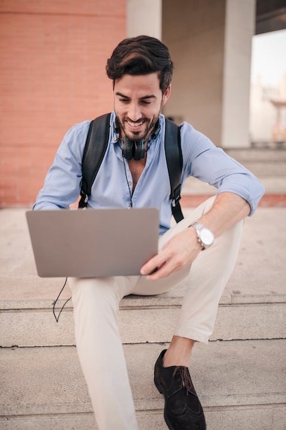 Young man sitting on staircase working on laptop