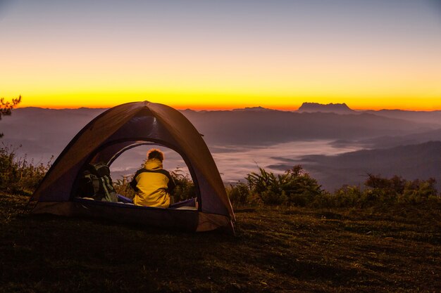 겨울에 산 풍경을보고 텐트에 앉아있는 젊은 남자
