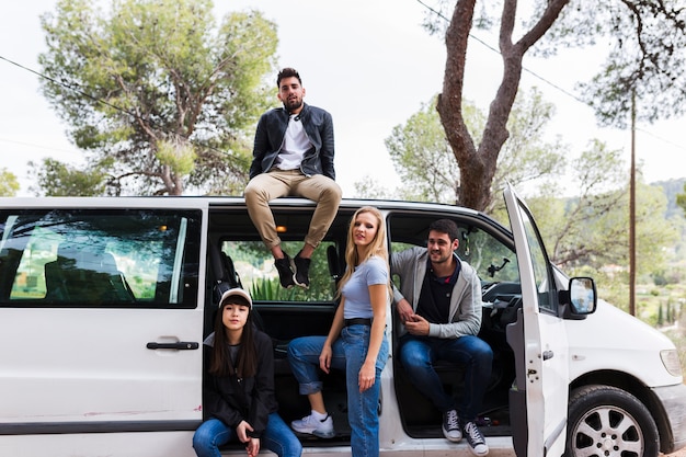 Free photo young man sitting on top of car