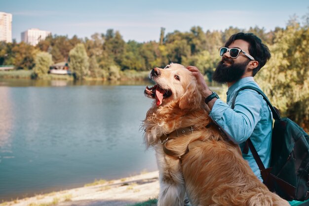 Young man sitting with his dog on the chair in the park