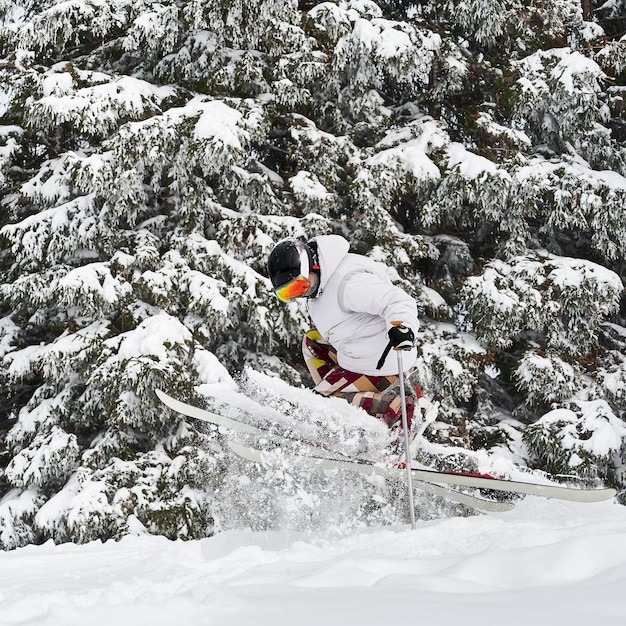 Free photo young man on skis doing tricks with ski poles