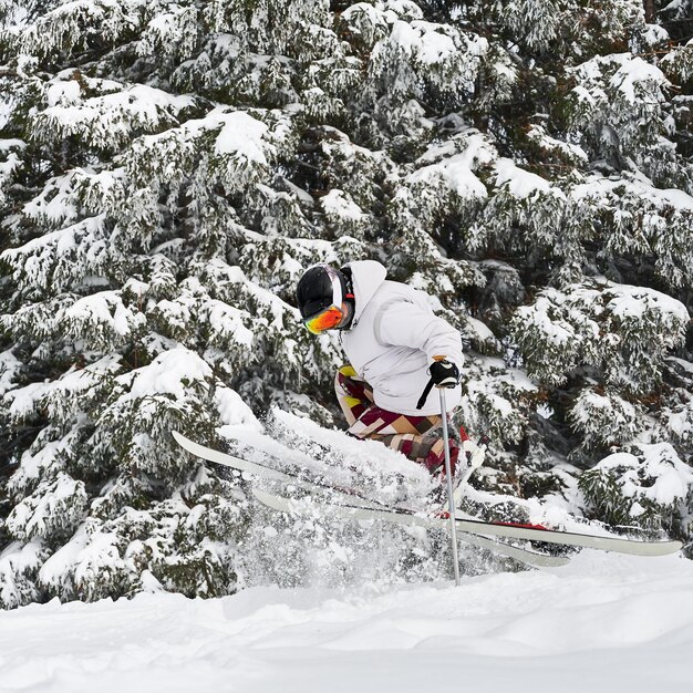 Молодой человек на лыжах делает трюки с лыжными палками