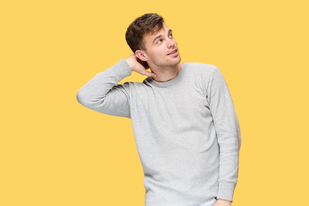 The young man smiling and looking away on yellow background