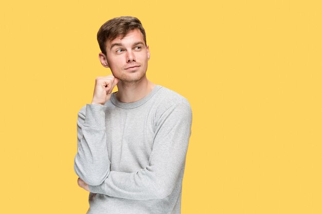 The young man smiling and looking away on yellow studio