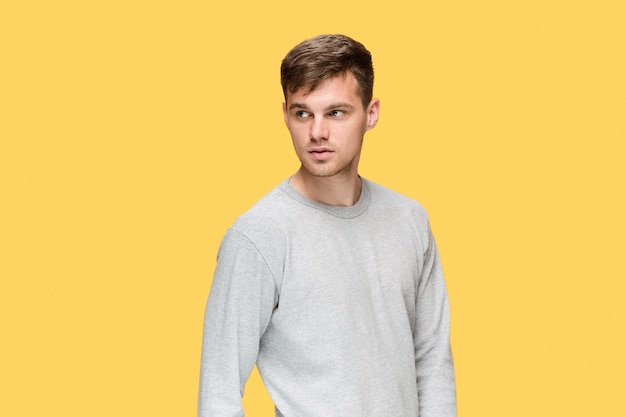 The young man smiling and looking at camera on yellow background