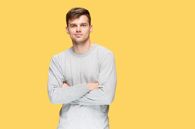 The young man smiling and looking at camera on yellow background