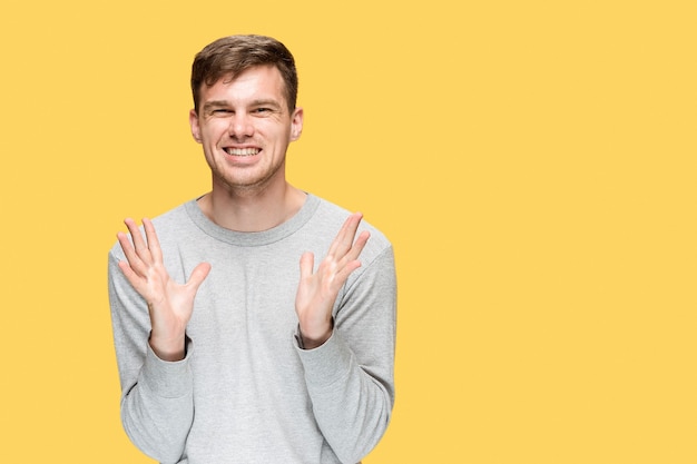 The young man smiling and looking at camera on yellow studio background