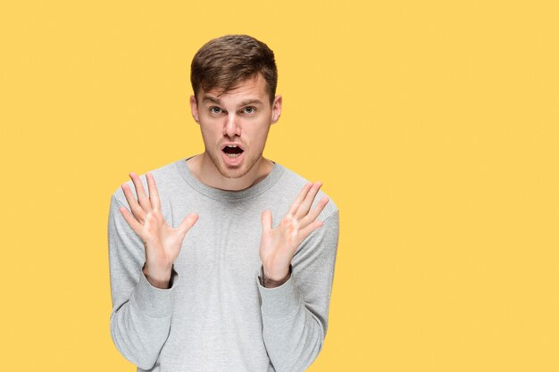 The young man smiling and looking at camera on yellow studio