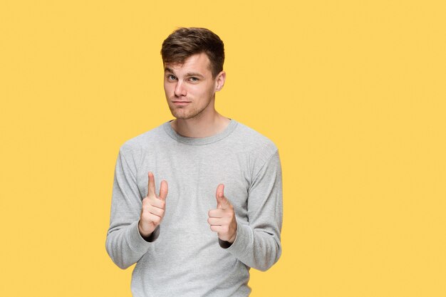 The young man smiling and looking and pointing at cameraaway