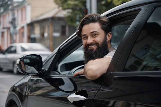 Молодой человек улыбается во время вождения автомобиля