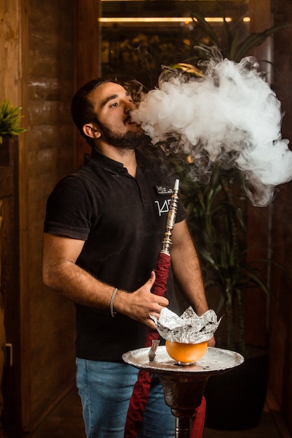 Young man smokes hookah with orange