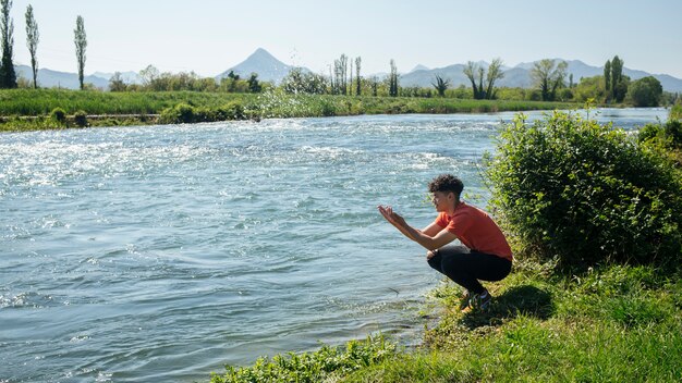 Giovane che spruzza acqua dal fiume