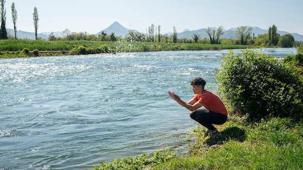 Young man splashing water from river