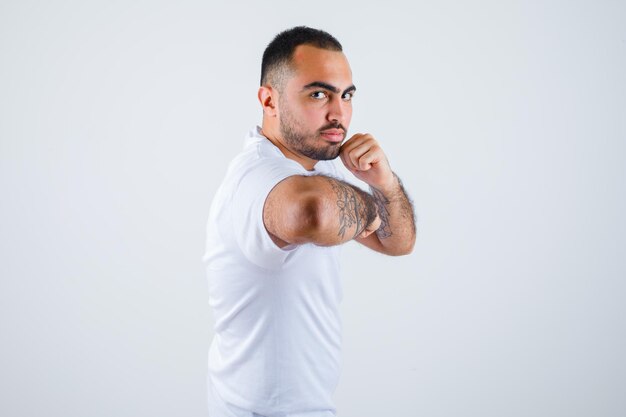 Young man standing in boxer pose in white t-shirt and looking serious