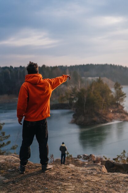 Young man standing on the edge of a cliff and pointing