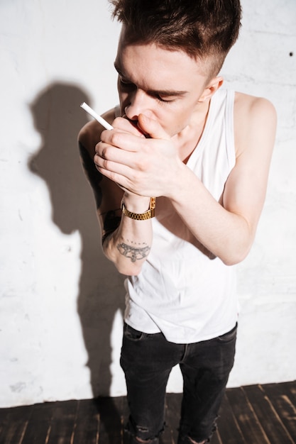 Young man standing on floor with cigarette posing