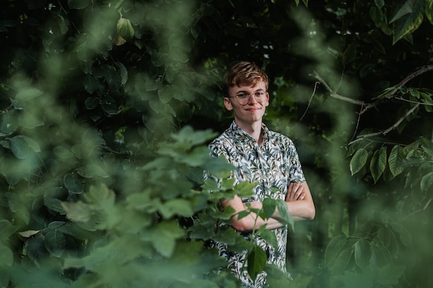 緑の植物の間に立っている若い男