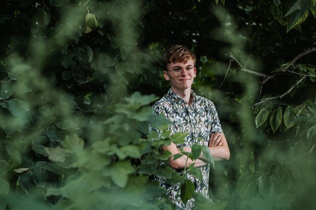 Young man standing between green plants